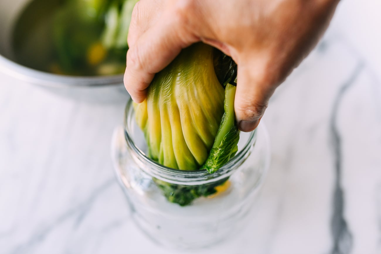 Adding mustard greens to glass jar
