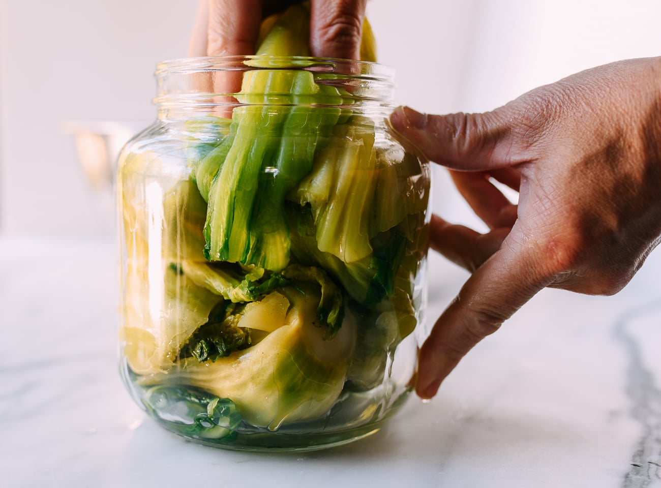 Squeezing mustard greens into pickling jar