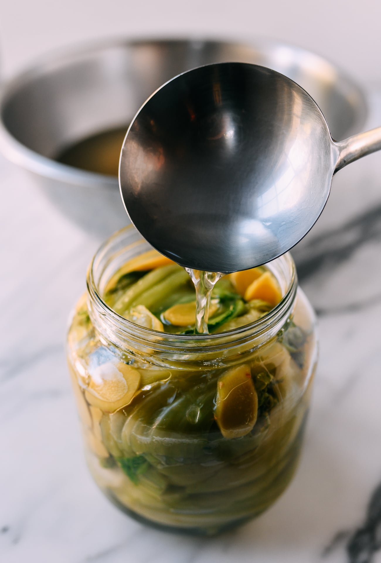 Adding brine to jar of mustard greens