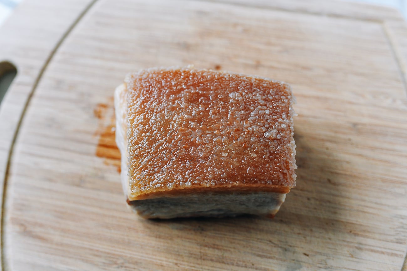 Blanched, fried, and soaked pork belly cooling on cutting board