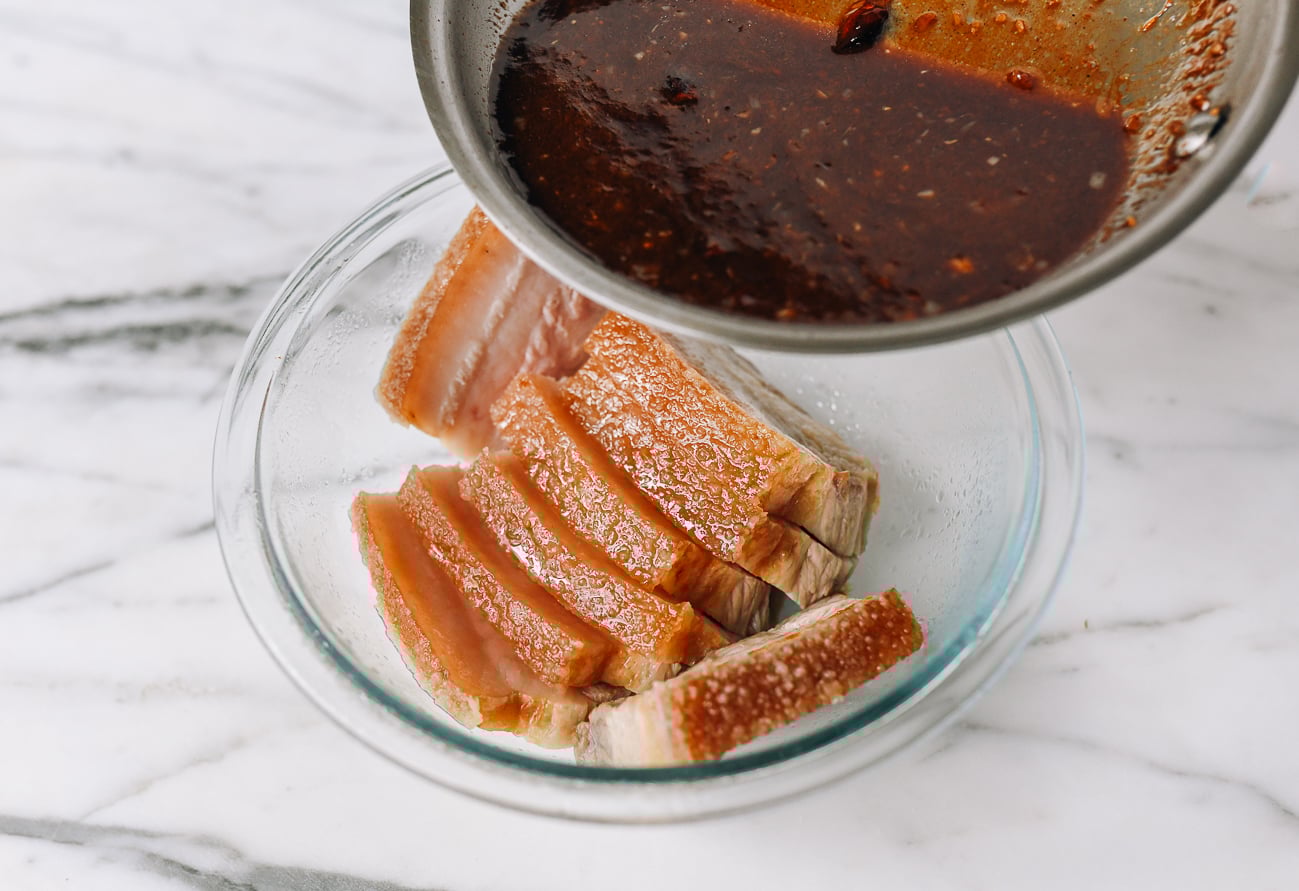 Pouring marinade sauce over pork belly