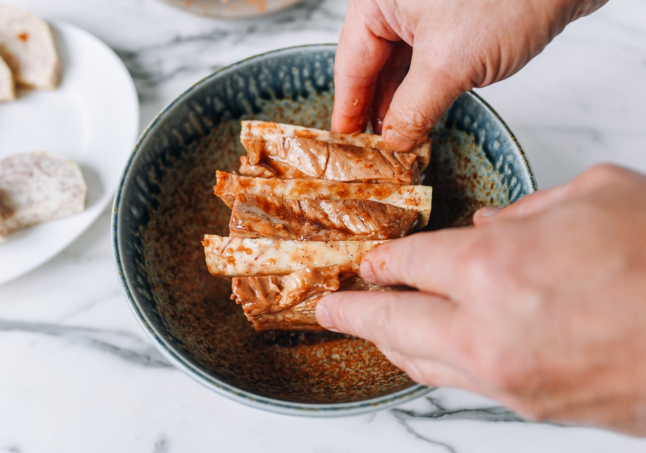 Arranging taro and pork belly in steaming bowl