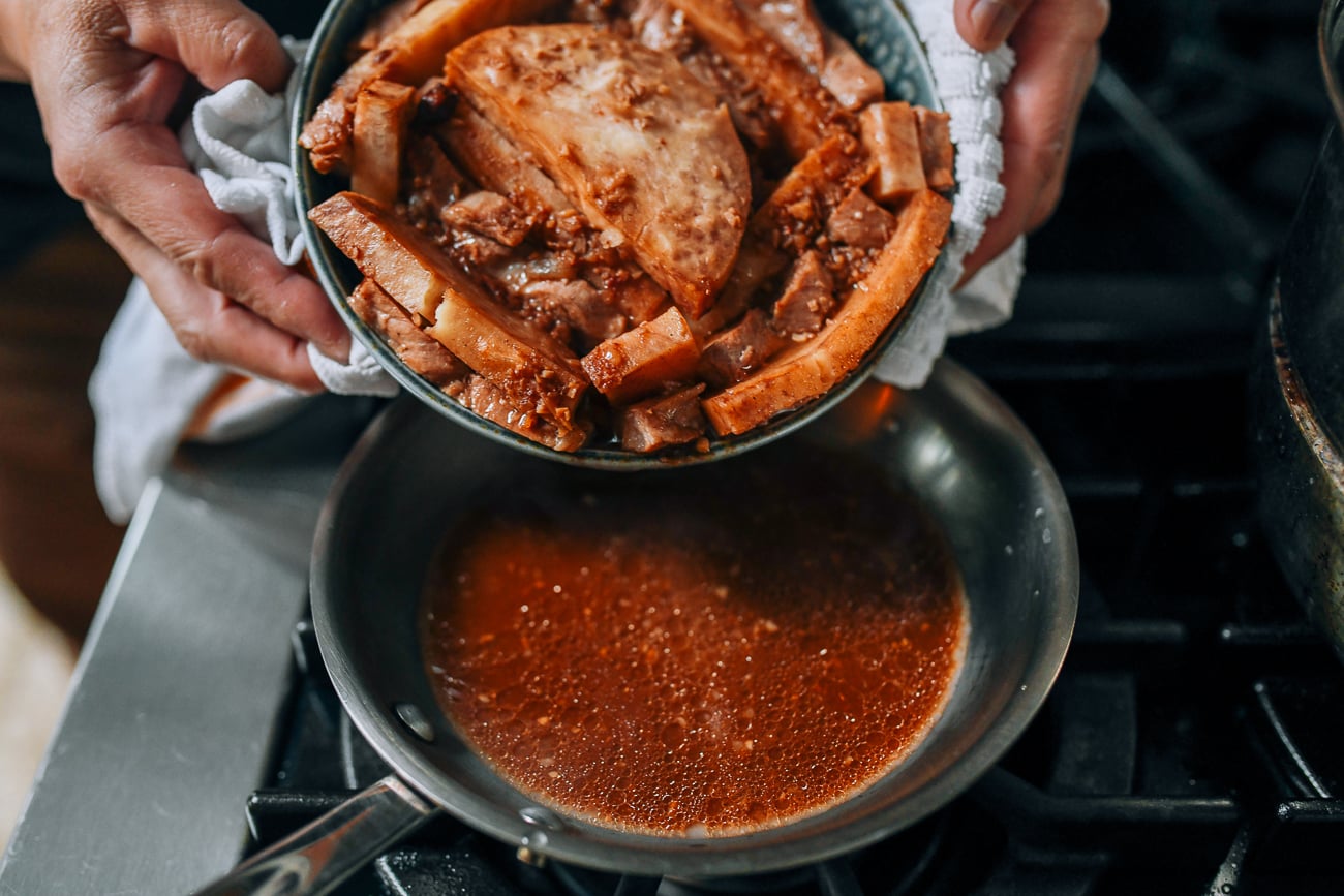 Pouring liquid from steamed taro and pork belly into saucepan