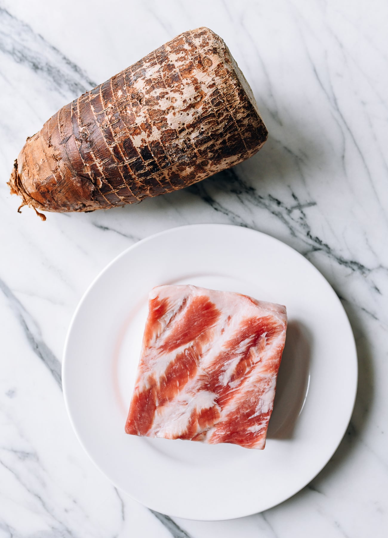 Large taro root and hunk of pork belly on white plate