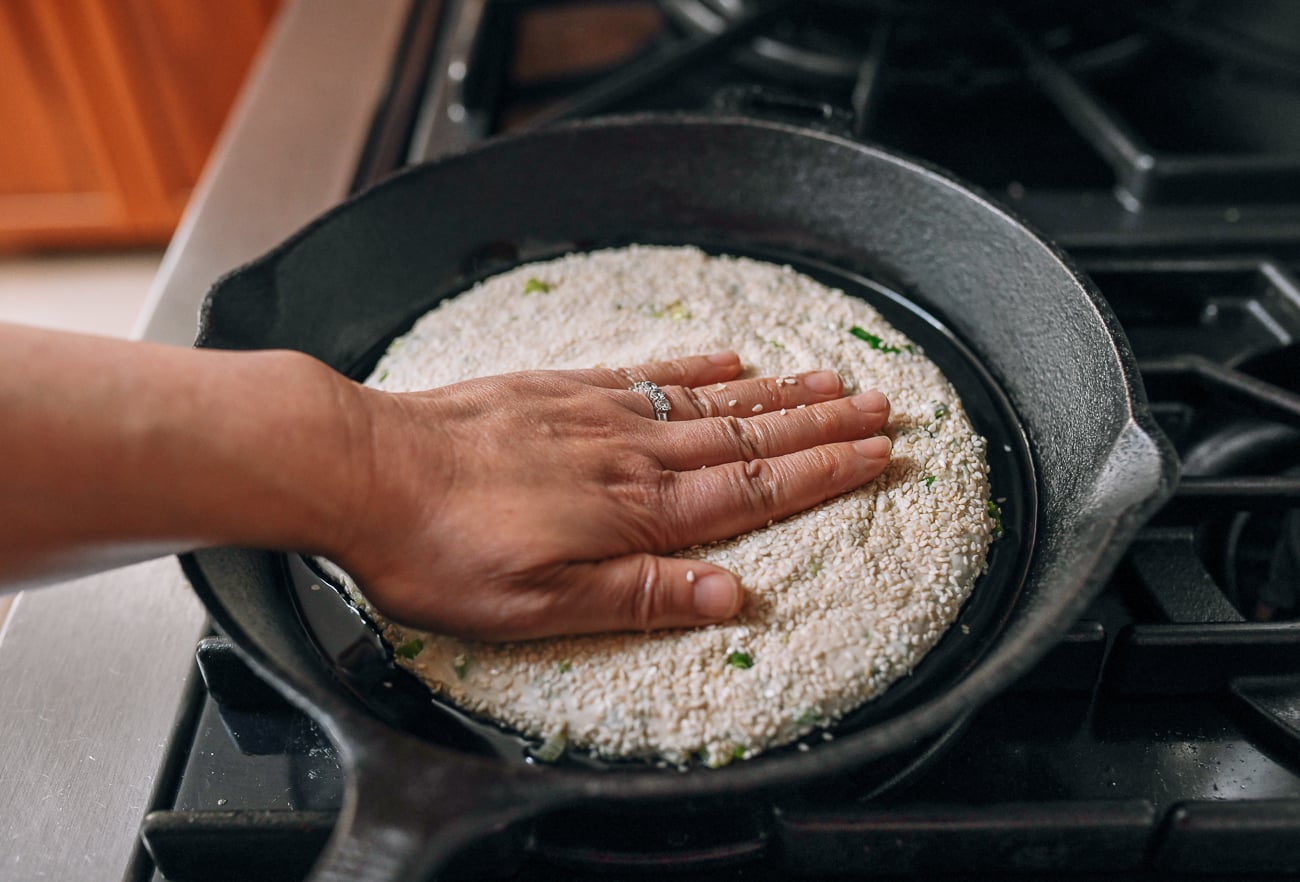 Pressing dough circle into cast iron pan