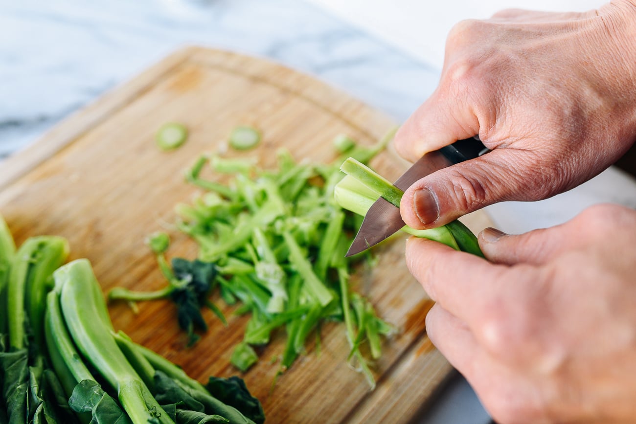 Trimming Chinese broccoli stems with a paring knife
