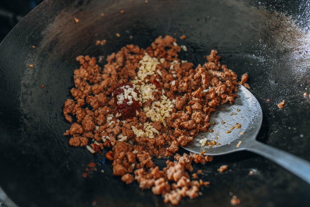 Adding spicy bean sauce and garlic to ground pork