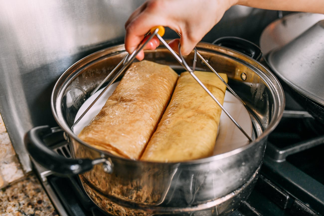 Putting bean curd sheet rolls into steamer