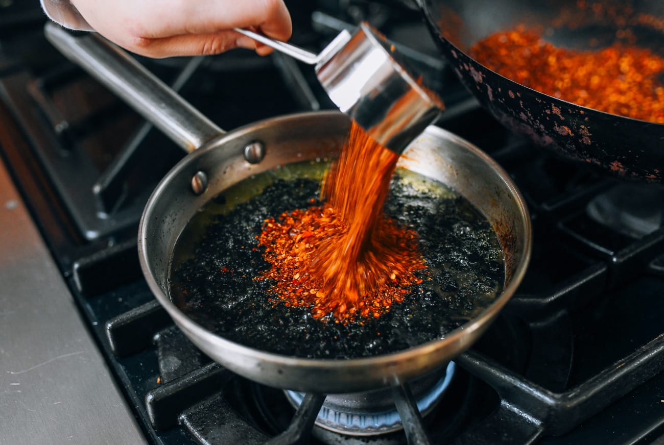 Pouring chili flakes into oil