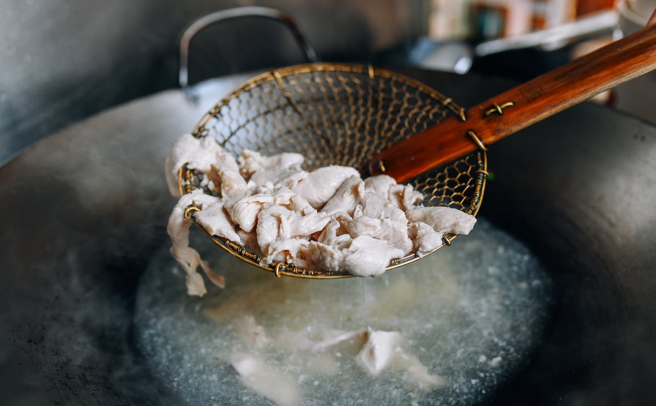 Removing blanched chicken from wok