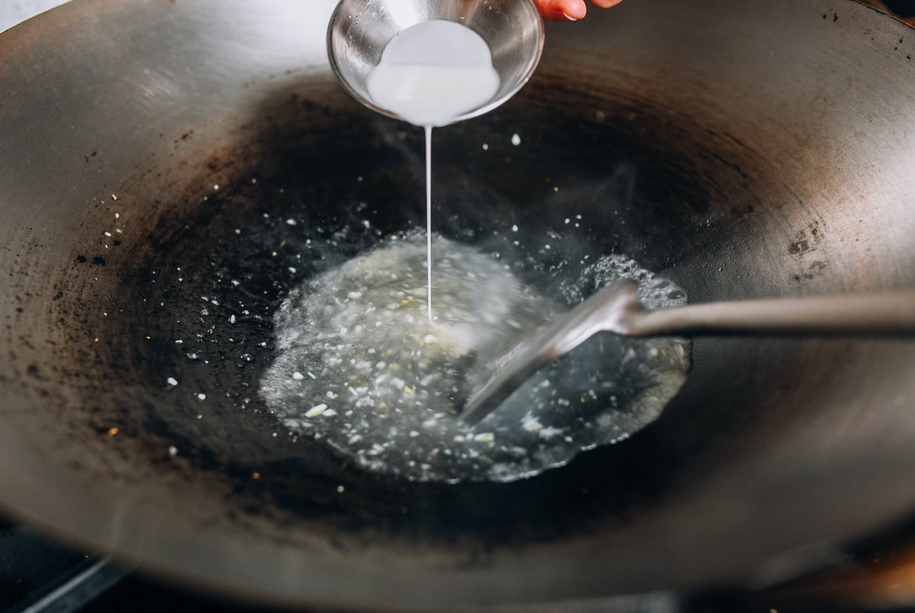Adding cornstarch slurry to sauce in wok