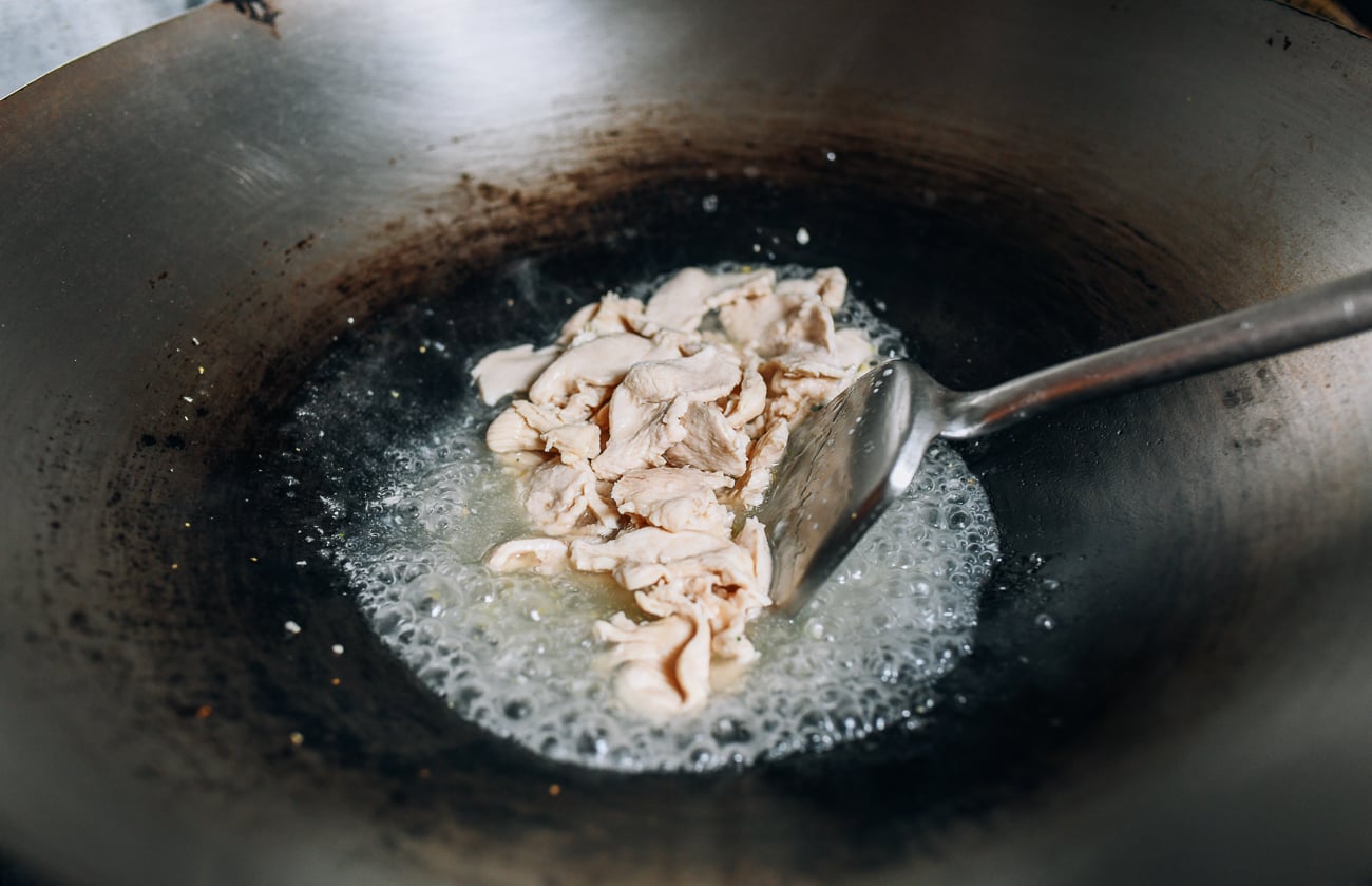 Adding chicken to sauce in wok