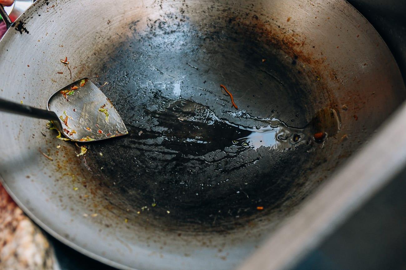 Scraping bits of food off of wok with spatula