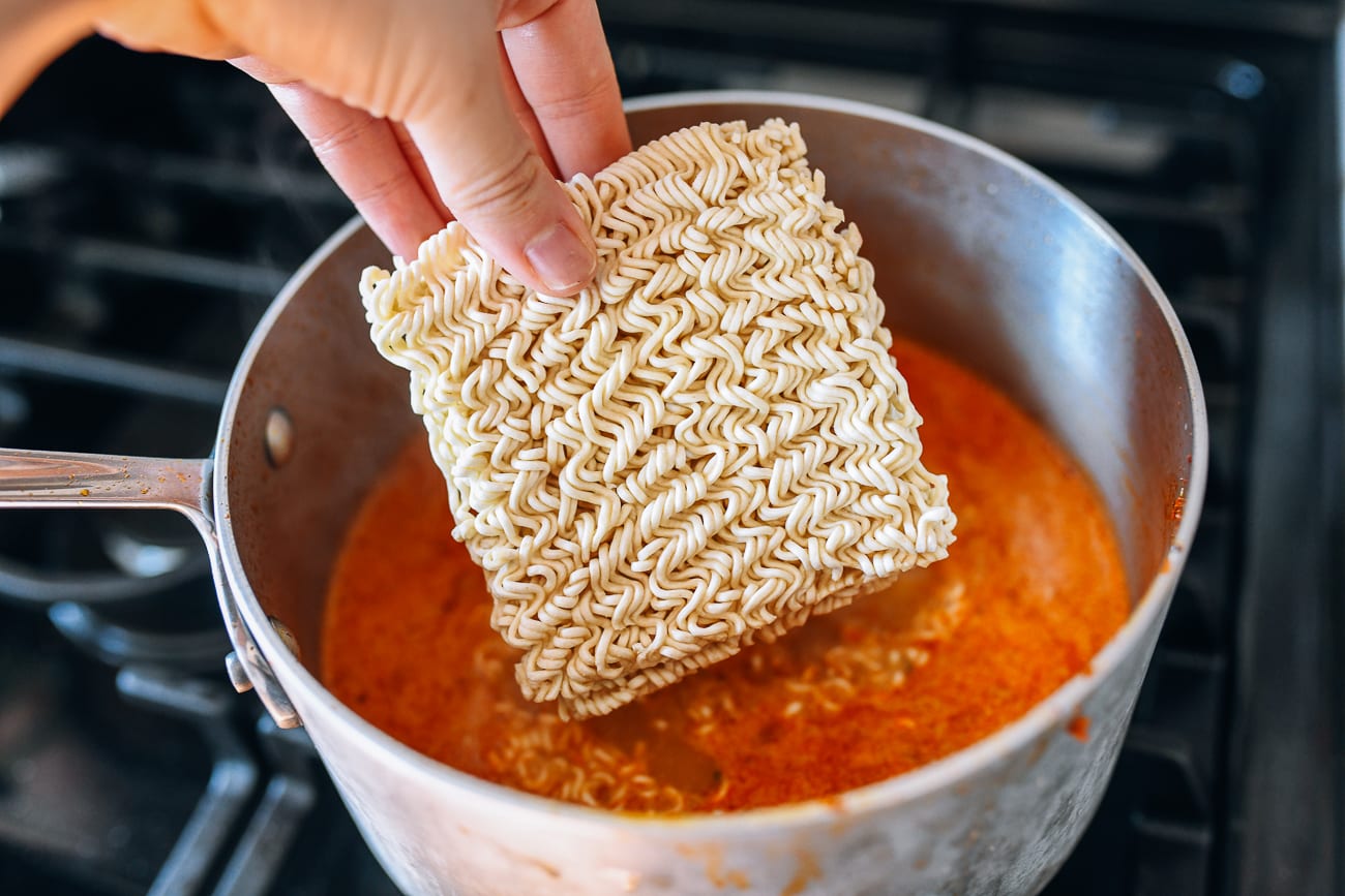 Adding instant noodles to pot of broth