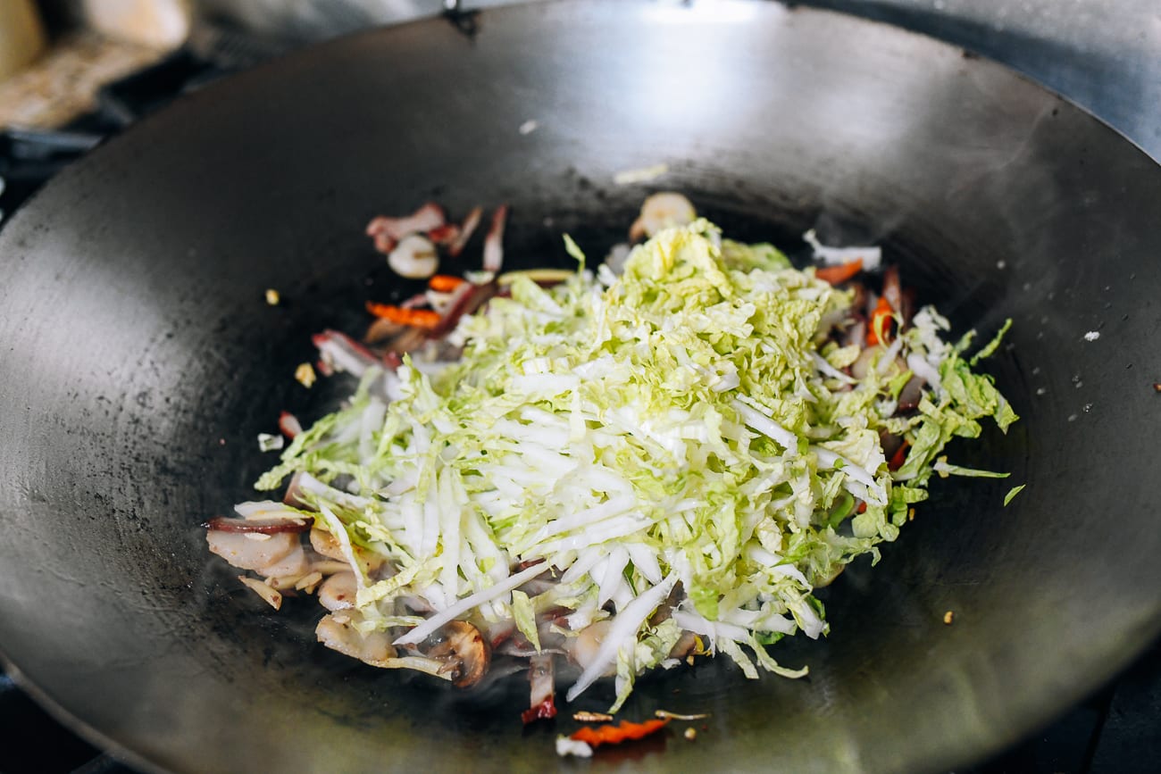 Adding shredded napa cabbage to wok