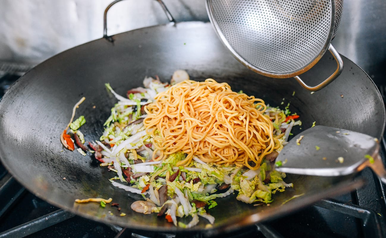 Adding lo mein noodles to wok