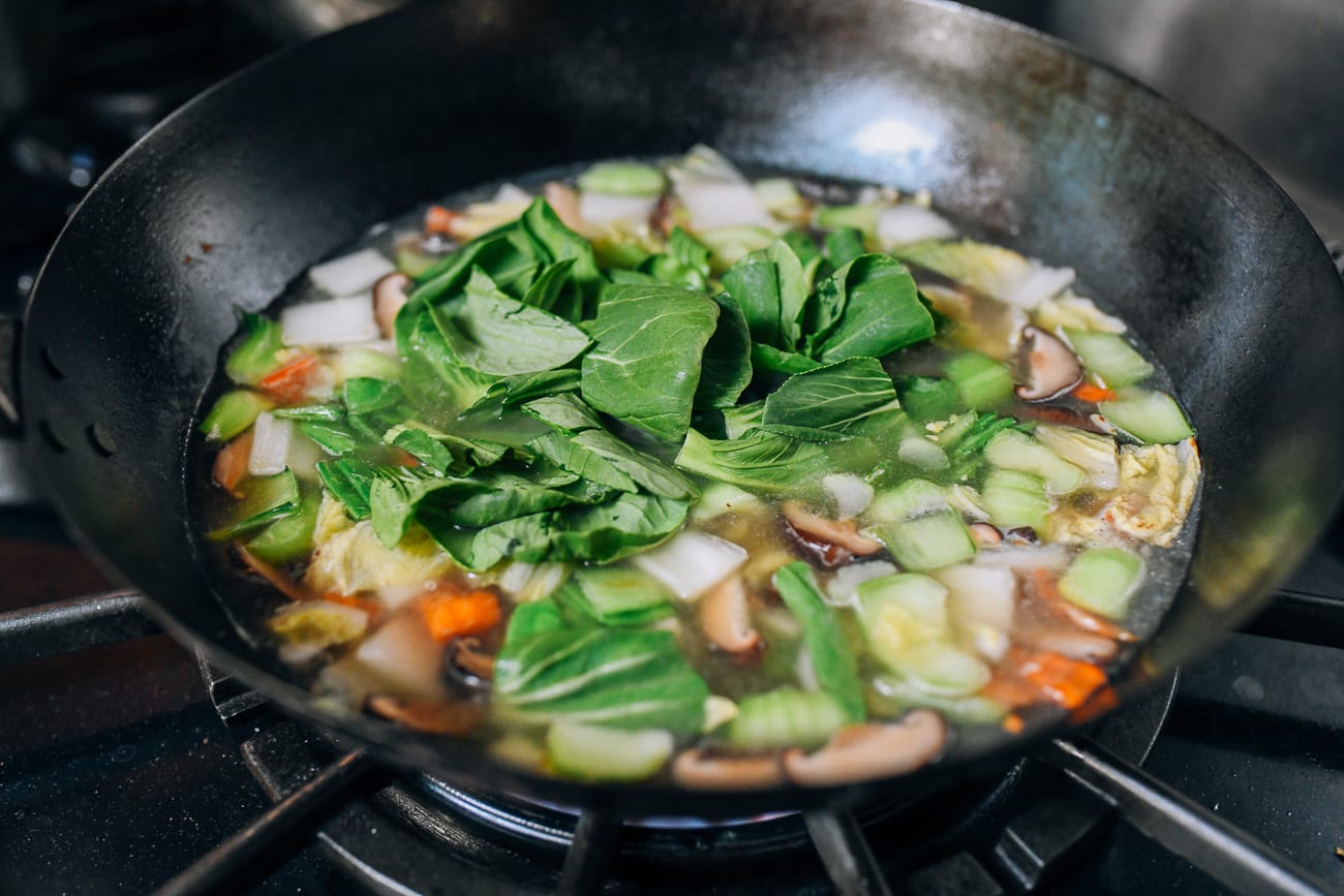 Adding leafy portions of baby bok choy to soup