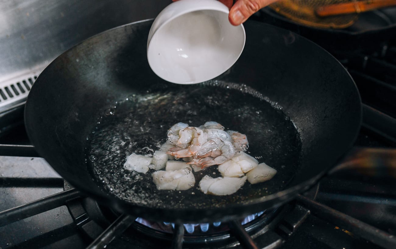 Adding shrimp and scallops to boiling water in wok