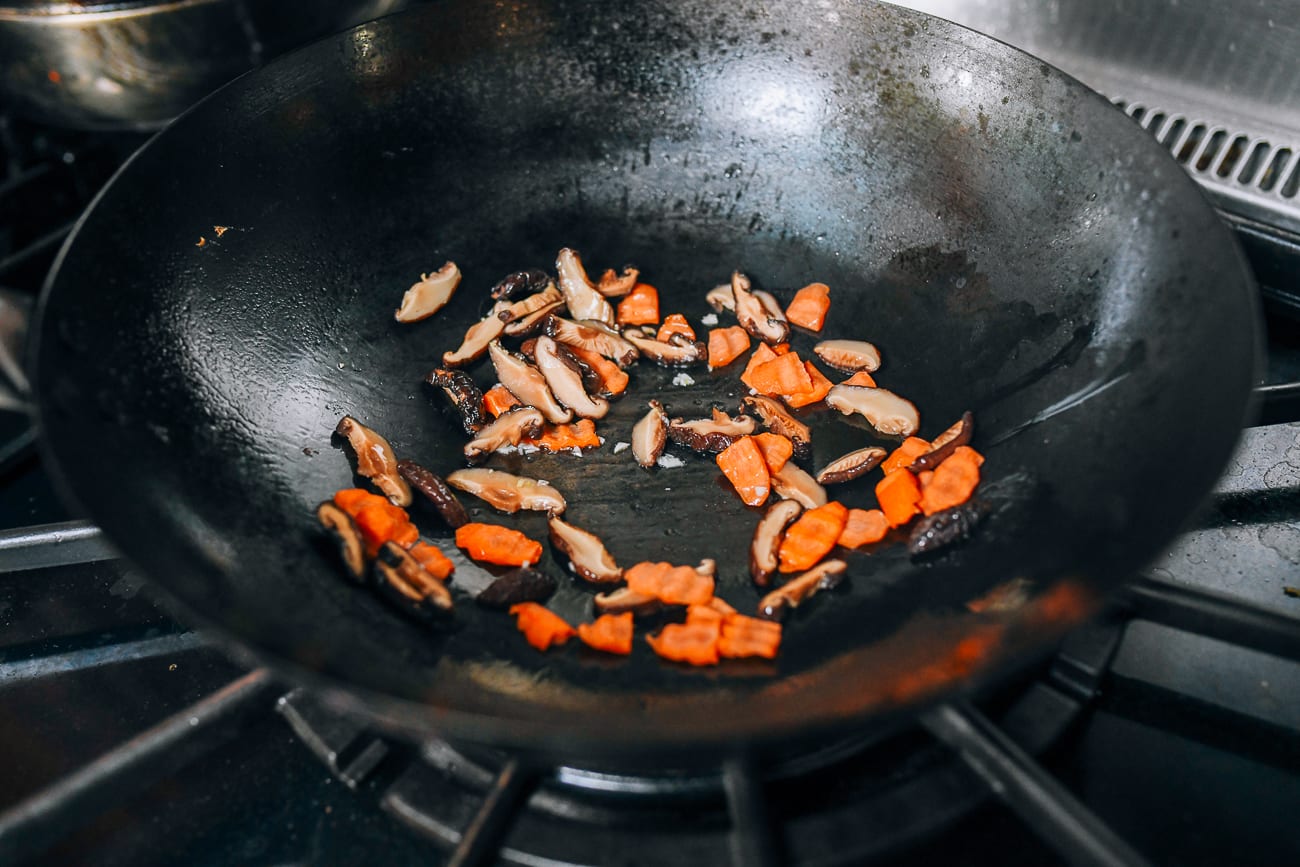 Cooking garlic, carrots, and shiitake mushrooms in wok