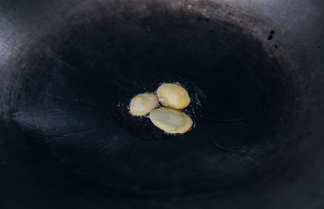 Frying ginger slices in wok