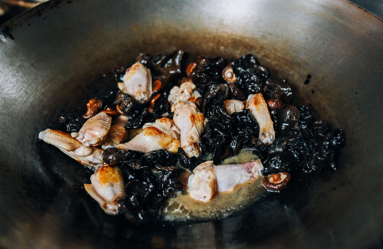 Adding braising liquid to mushrooms and chicken