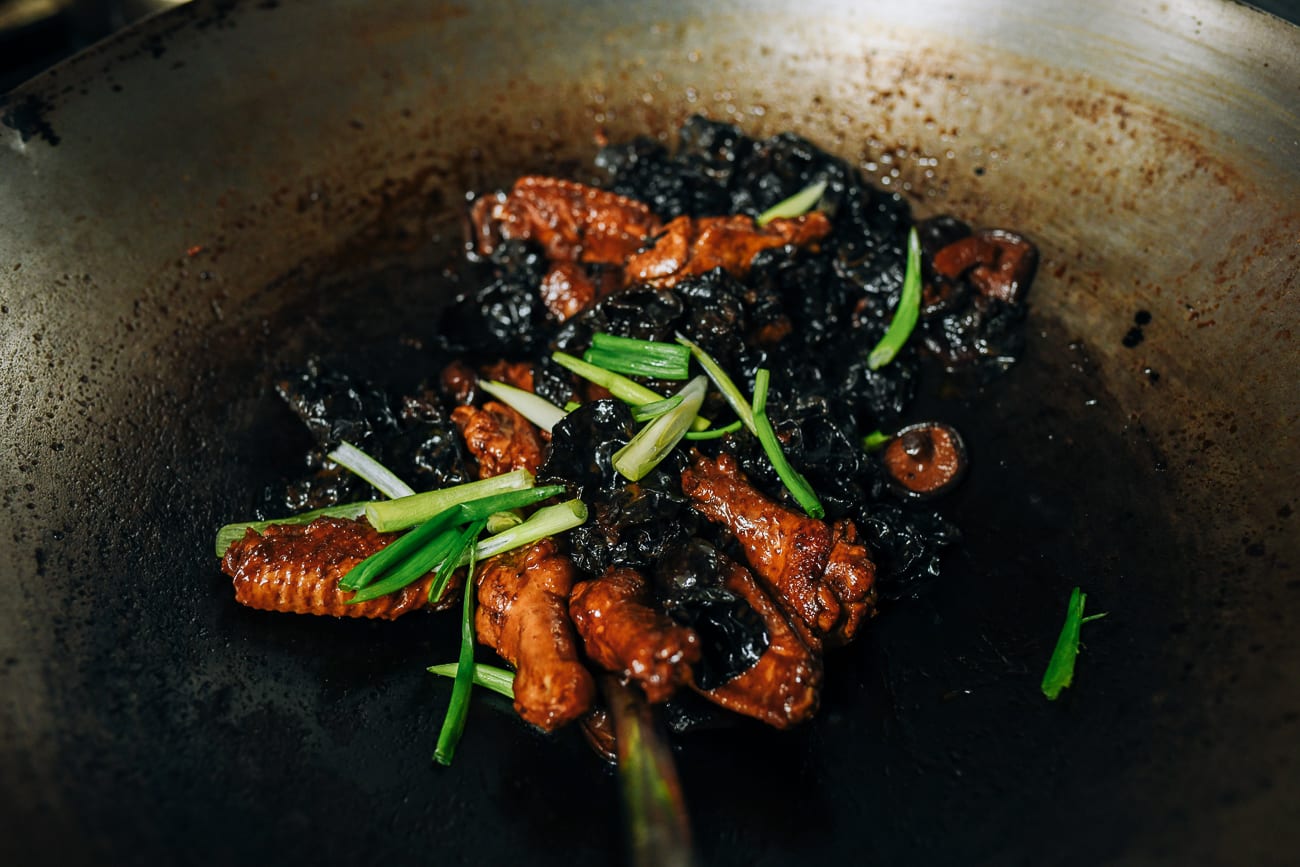 Stirring scallions into chicken and mushrooms