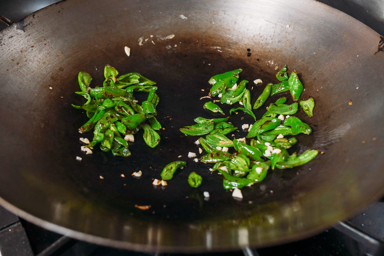 Adding peppers to wok with garlic