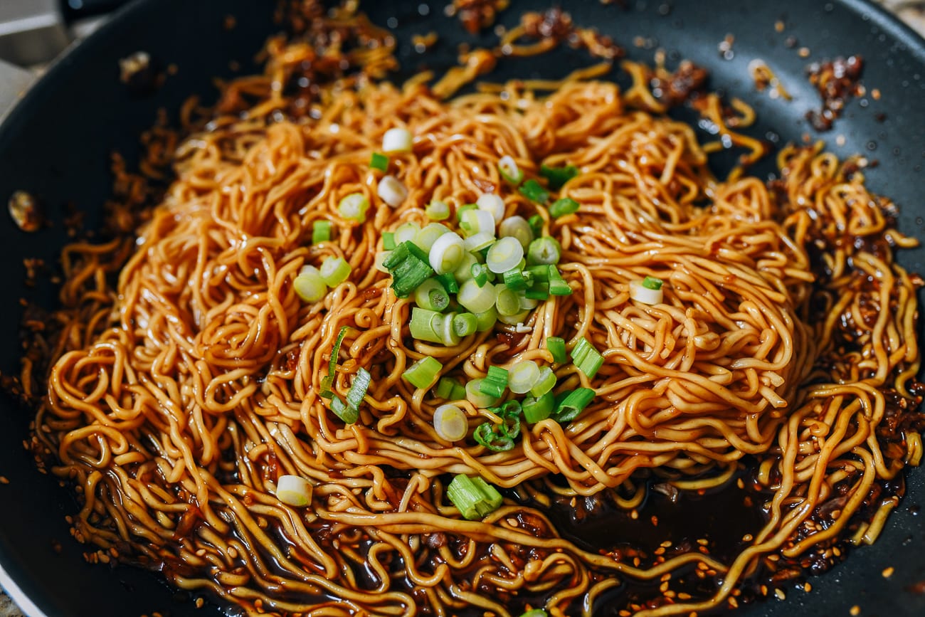 Mixing noodles in sauce with scallions
