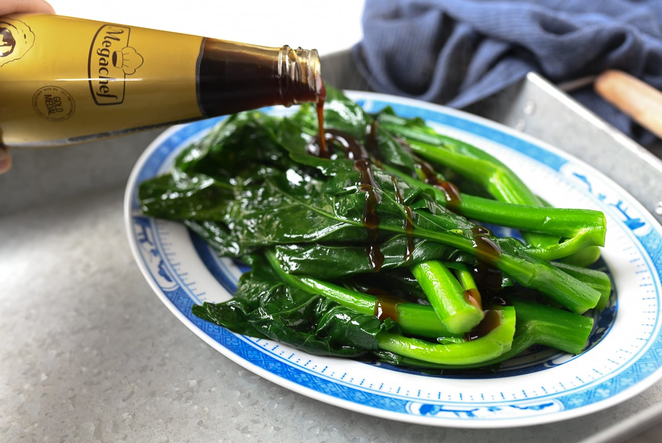 Drizzling oyster sauce over gai lan
