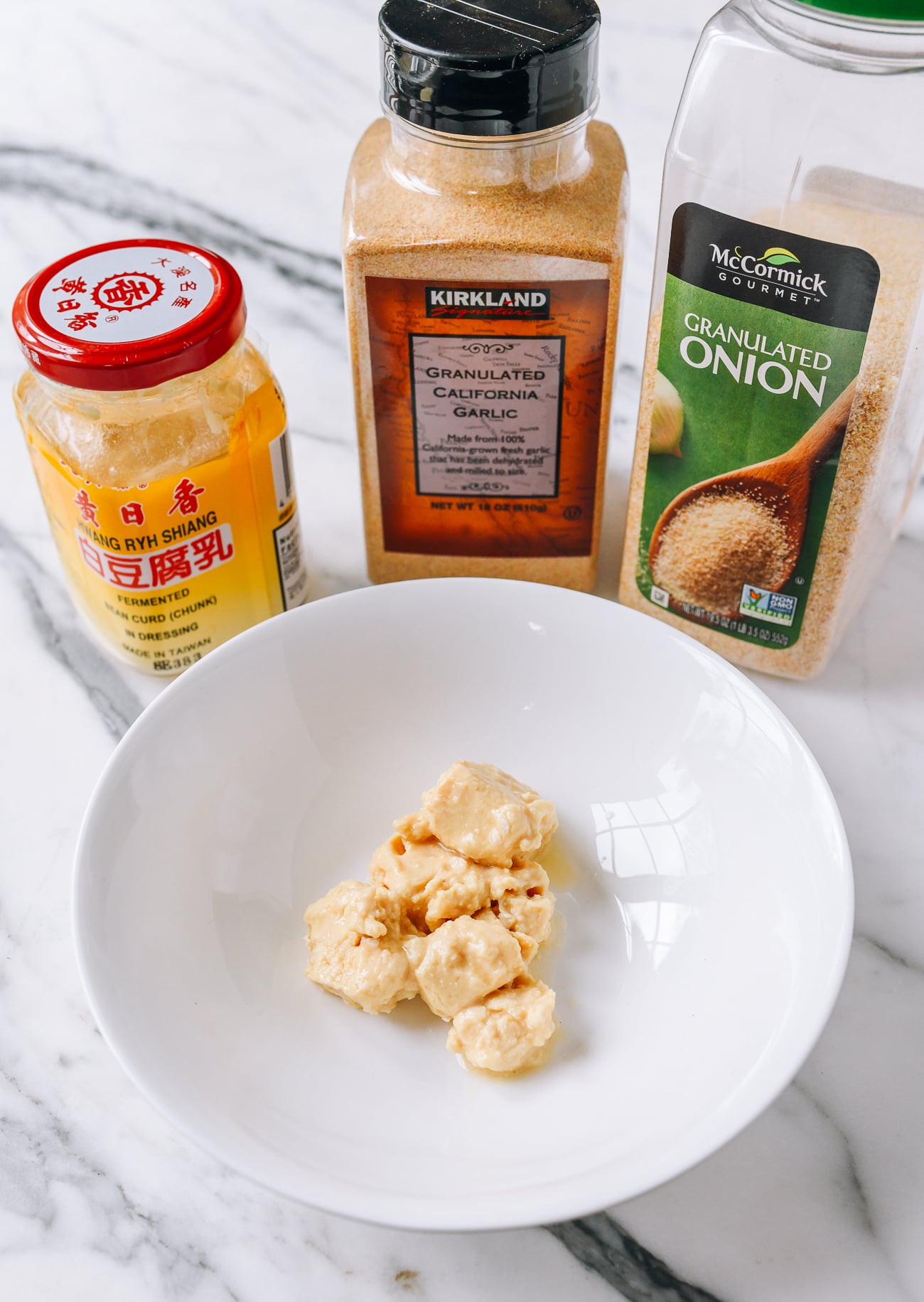 Fermented tofu in small bowl with garlic powder and onion powder in background
