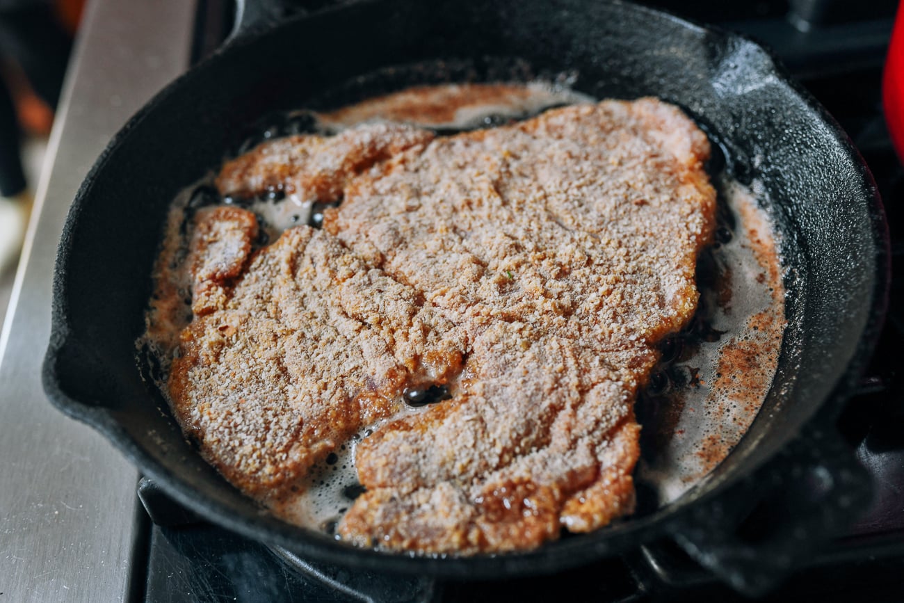 Frying one side of schnitzel in pan