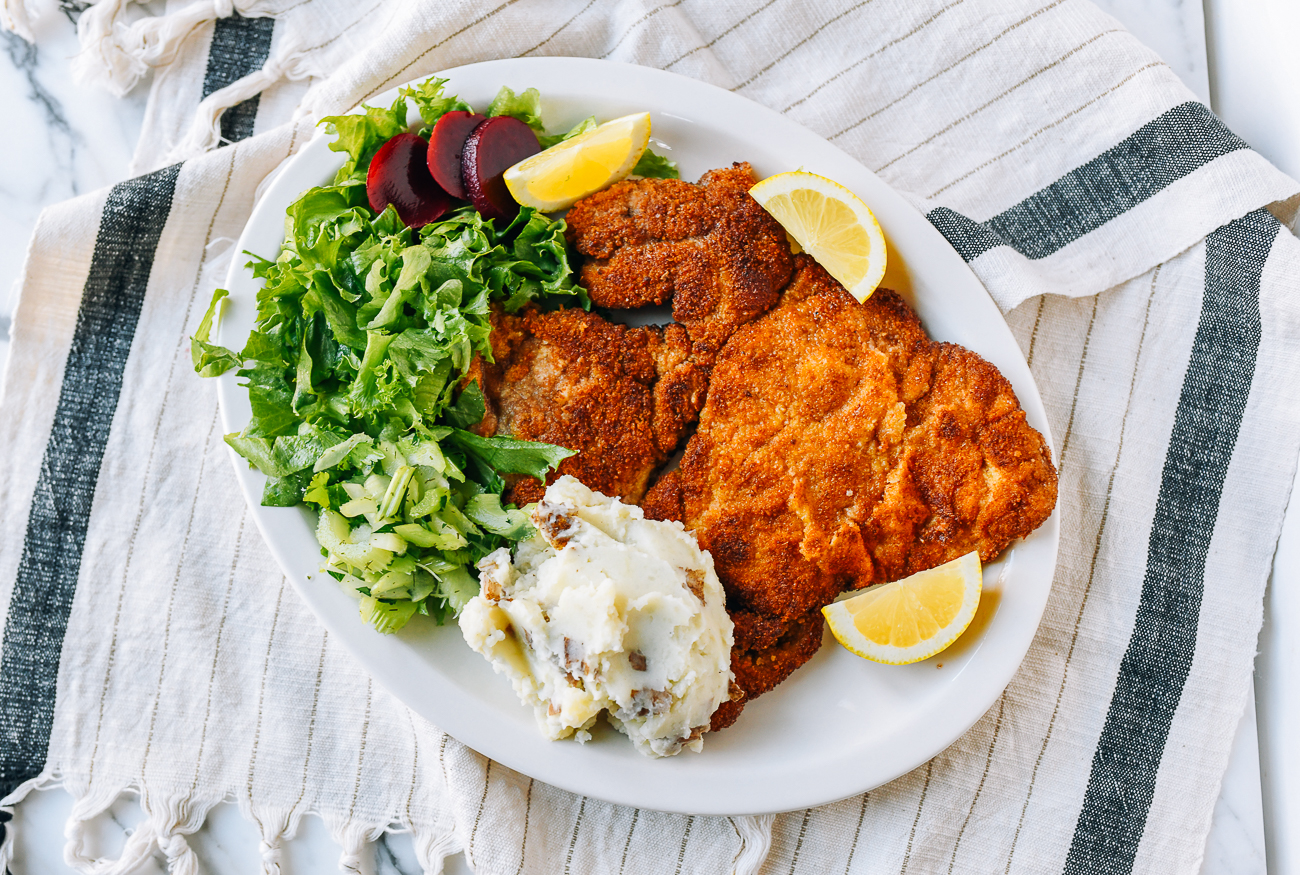 Pork schnitzel with mashed potatoes, salad, and lemon