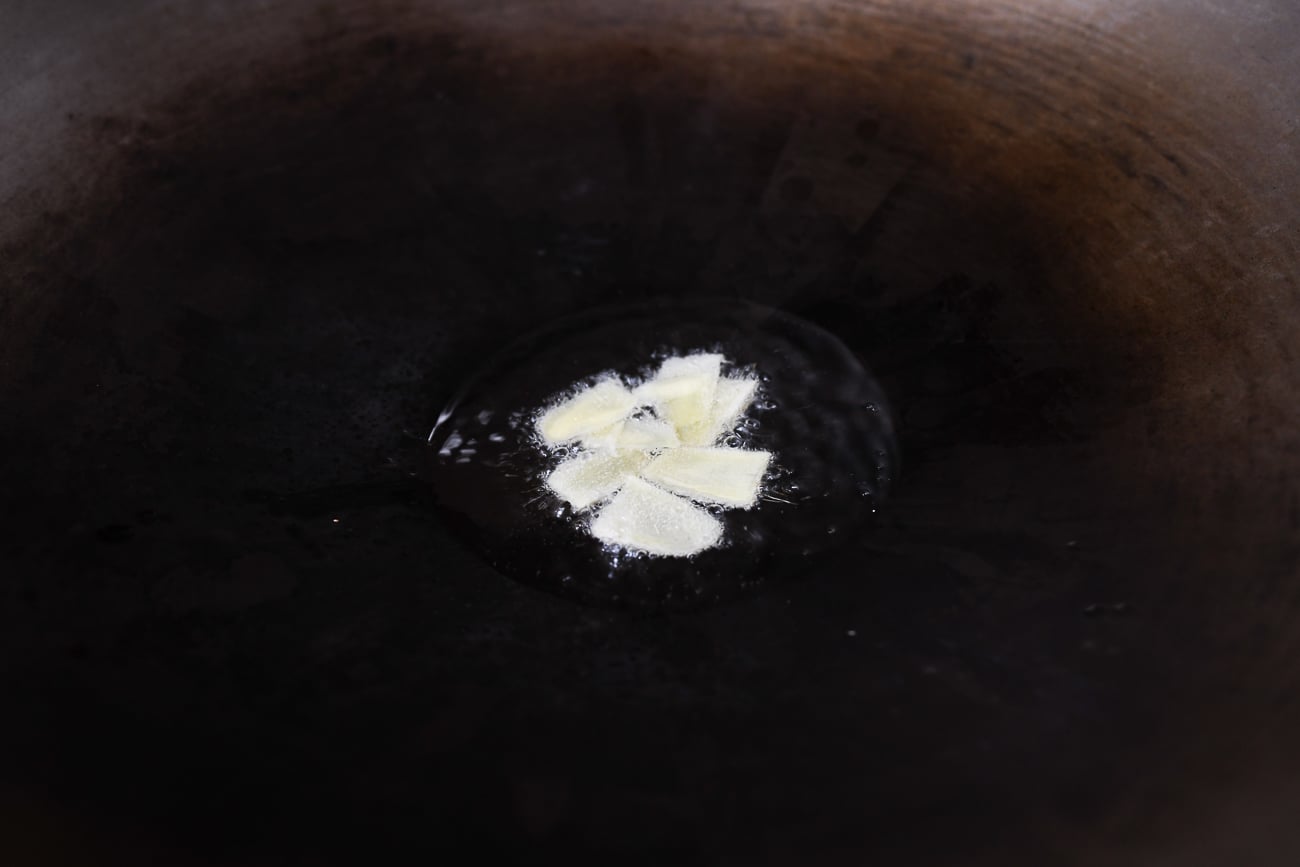 Cooking ginger slices in oil in a wok