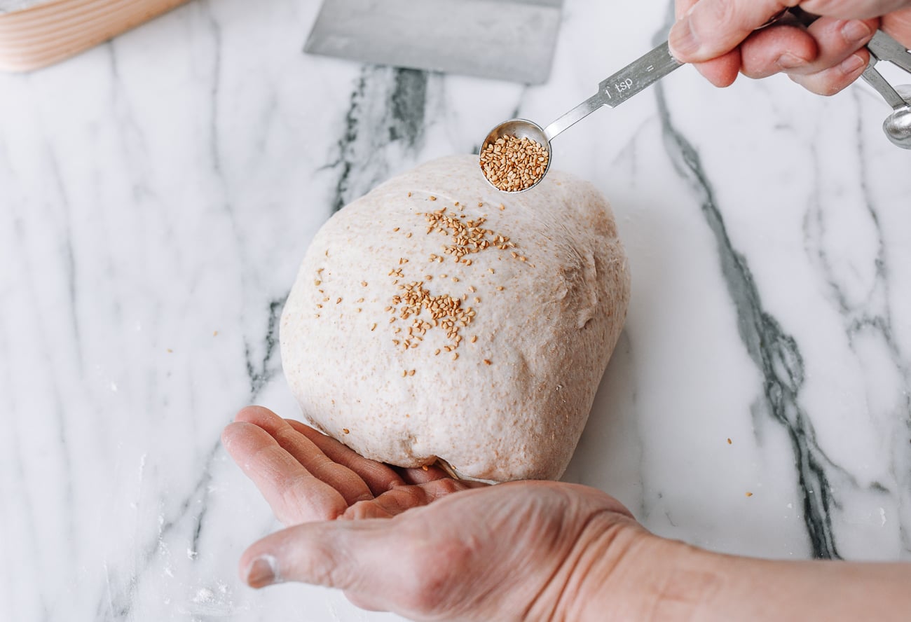 Sprinkling sesame seeds onto shaped dough