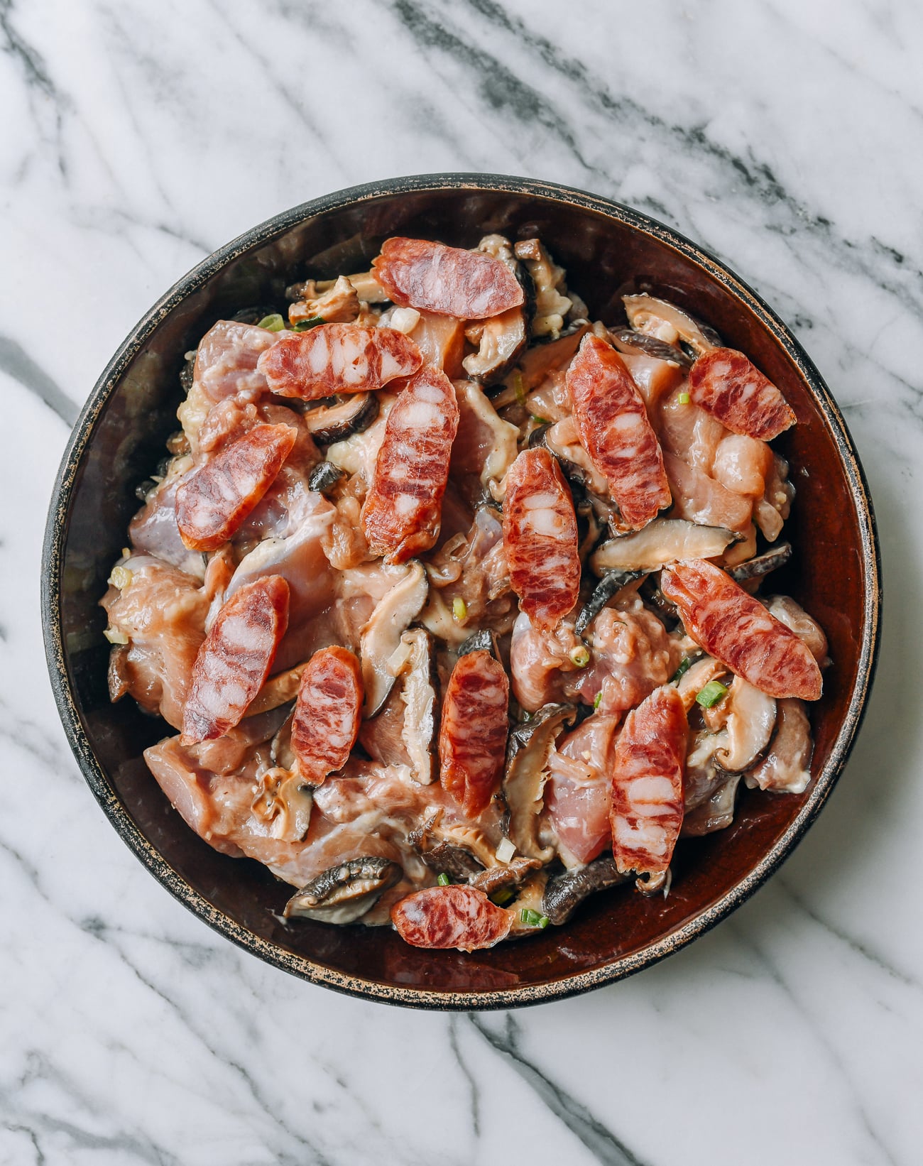 Sliced lap cheong scattered over marinated chicken