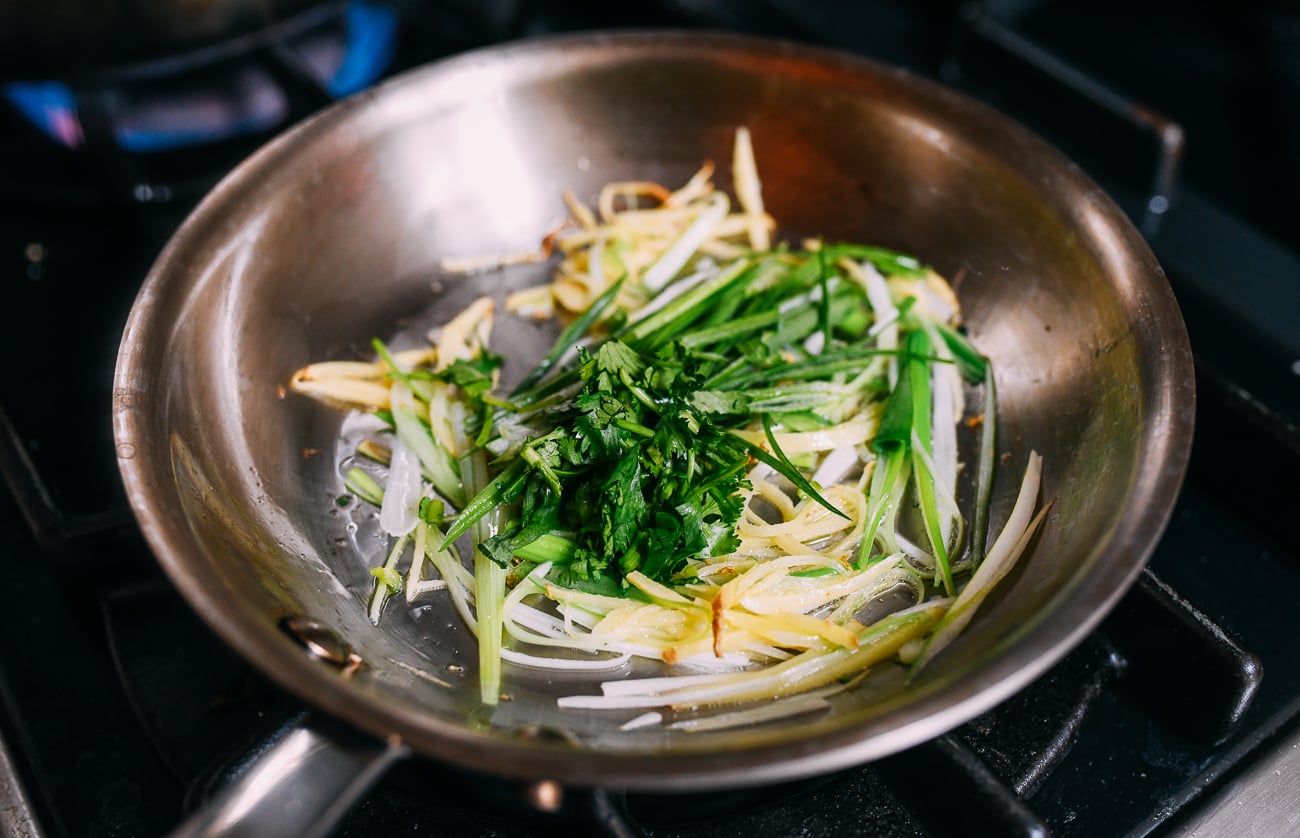 Adding green parts of scallions and cilantro