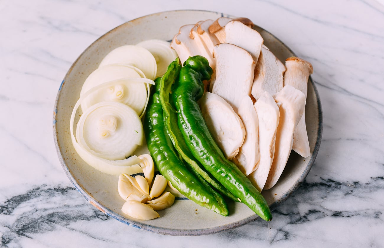 Sliced onions, peppers, king oyster mushrooms, and garlic cloves