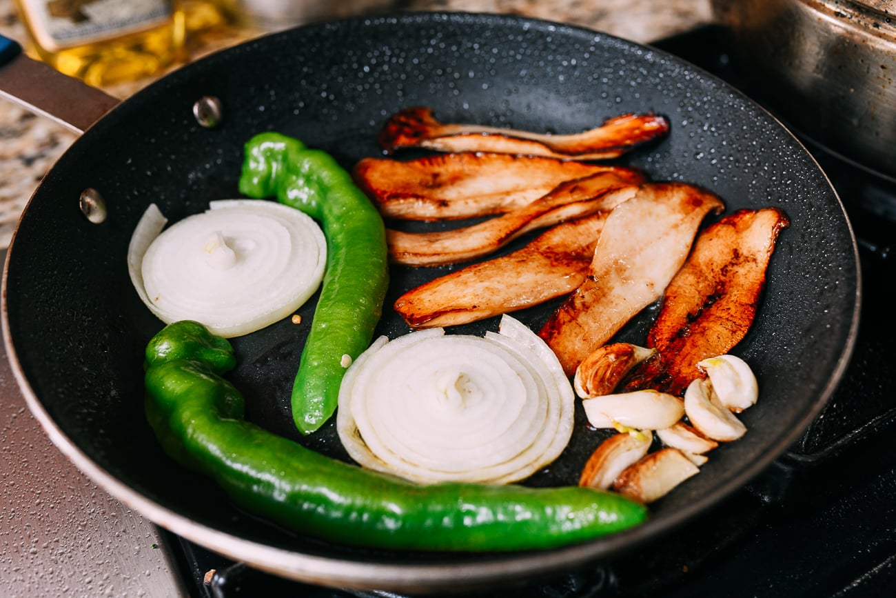 Long hot peppers, onions, and garlic in pan with mushrooms