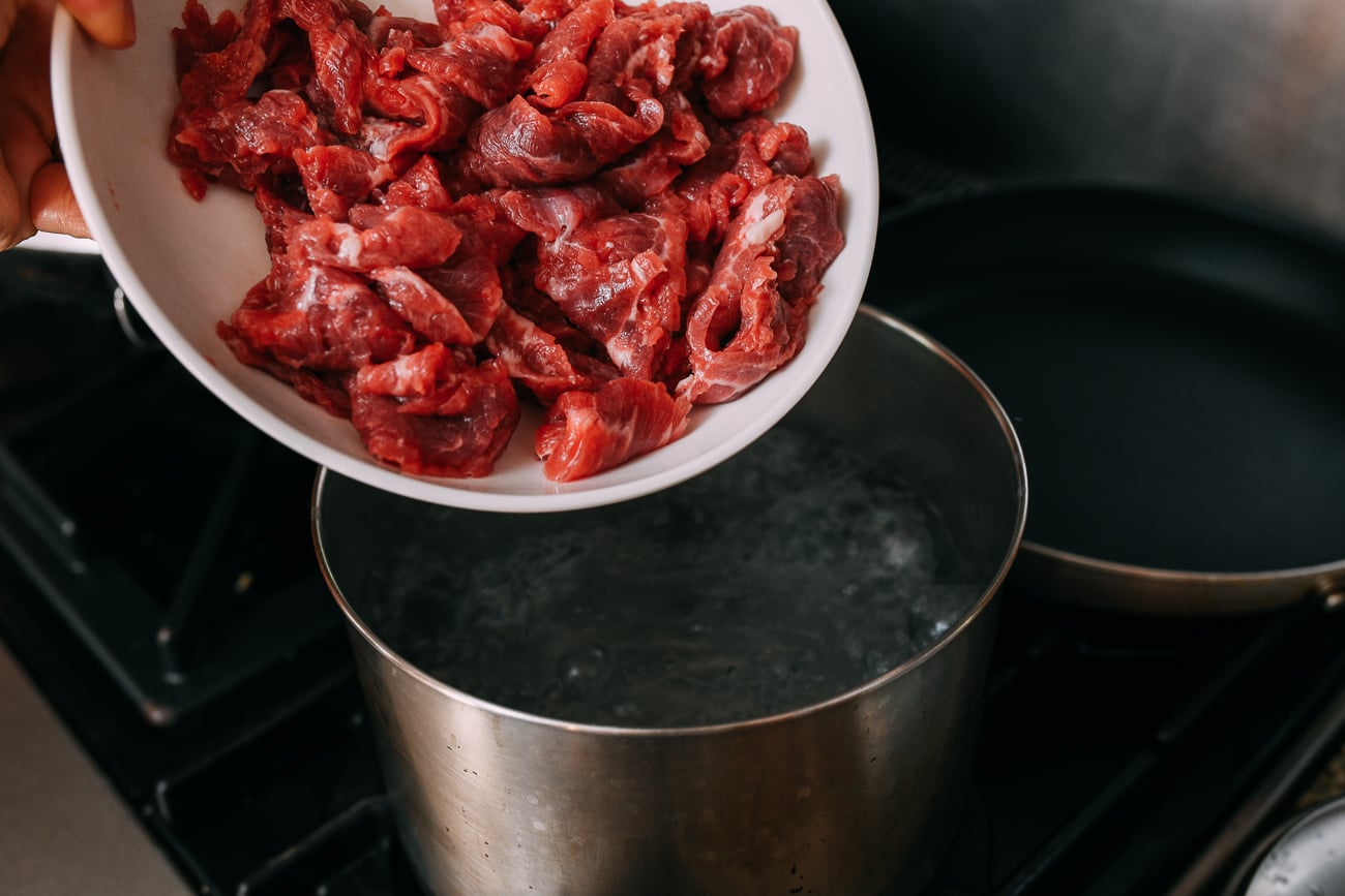 Adding marinated beef slices to boiling water