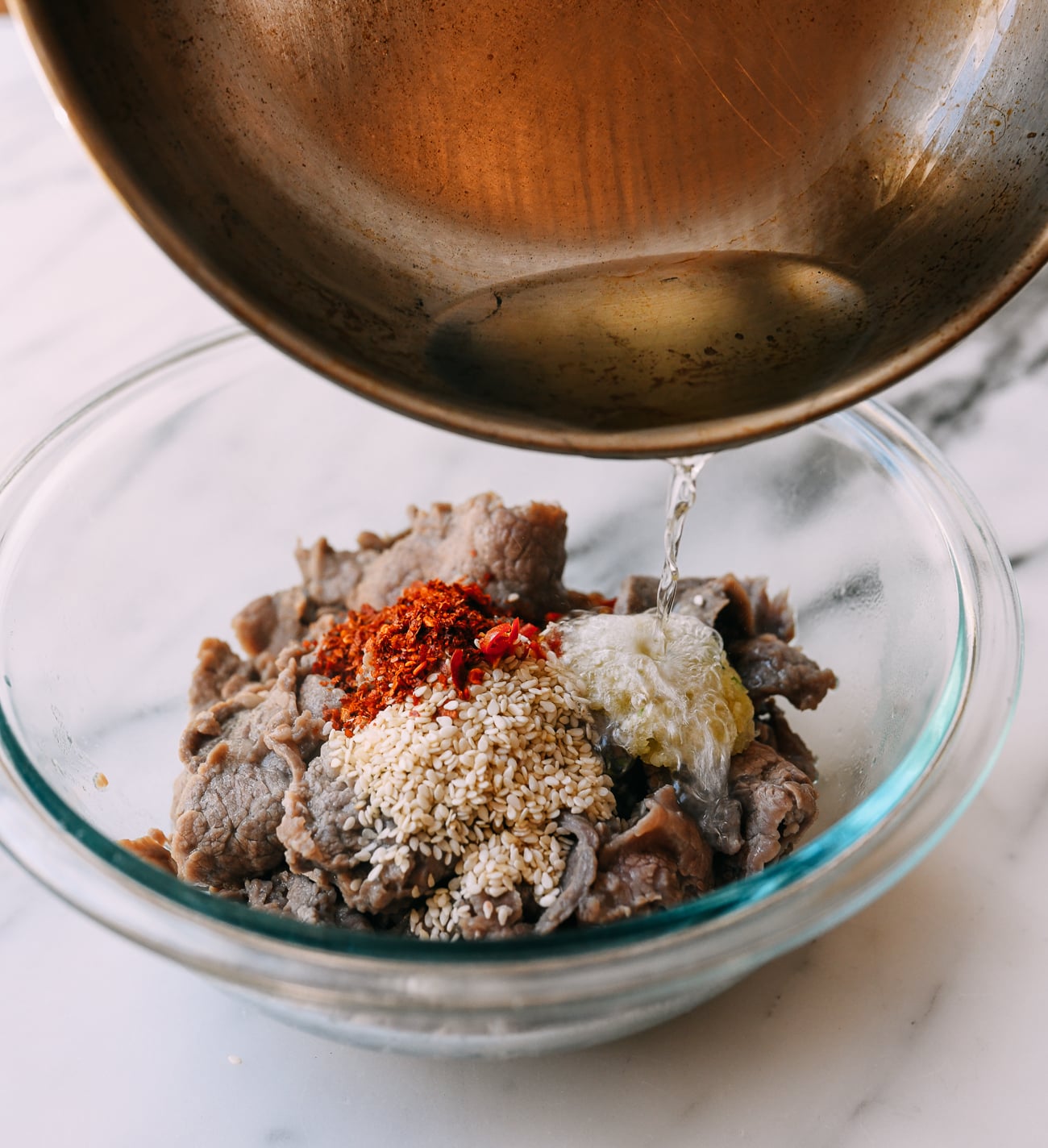 Pouring hot oil over seasonings on beef
