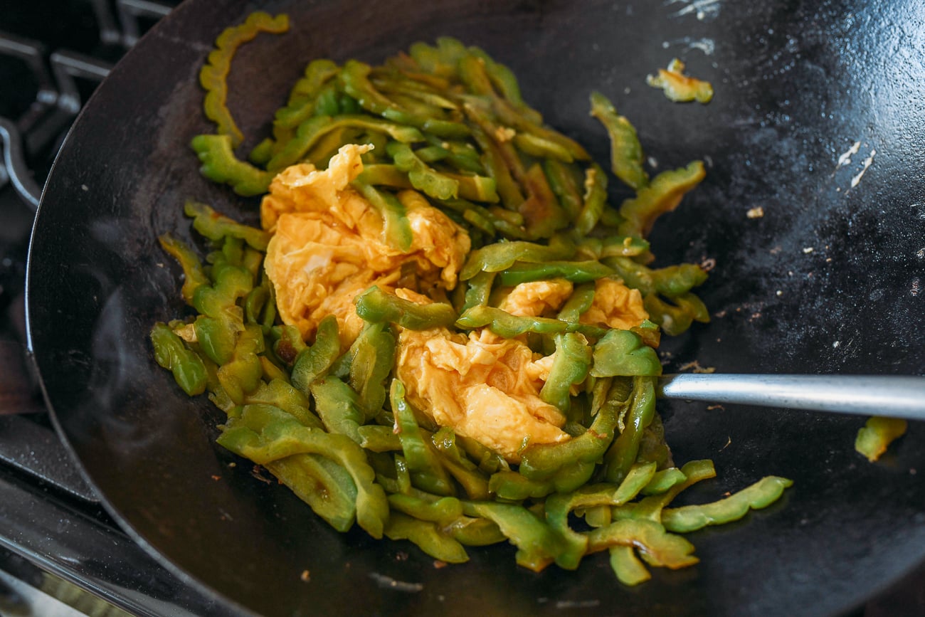 Stirring eggs into bitter melon in wok