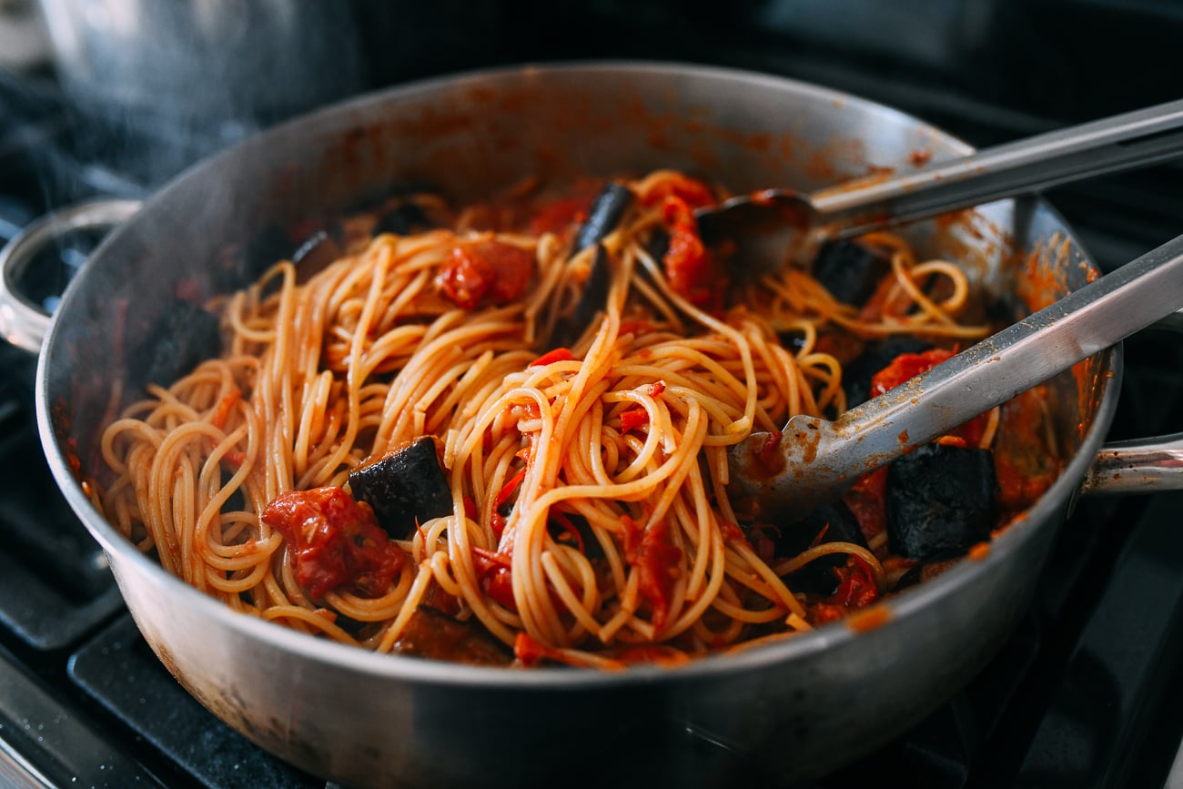Tossing pasta alla norma in skillet