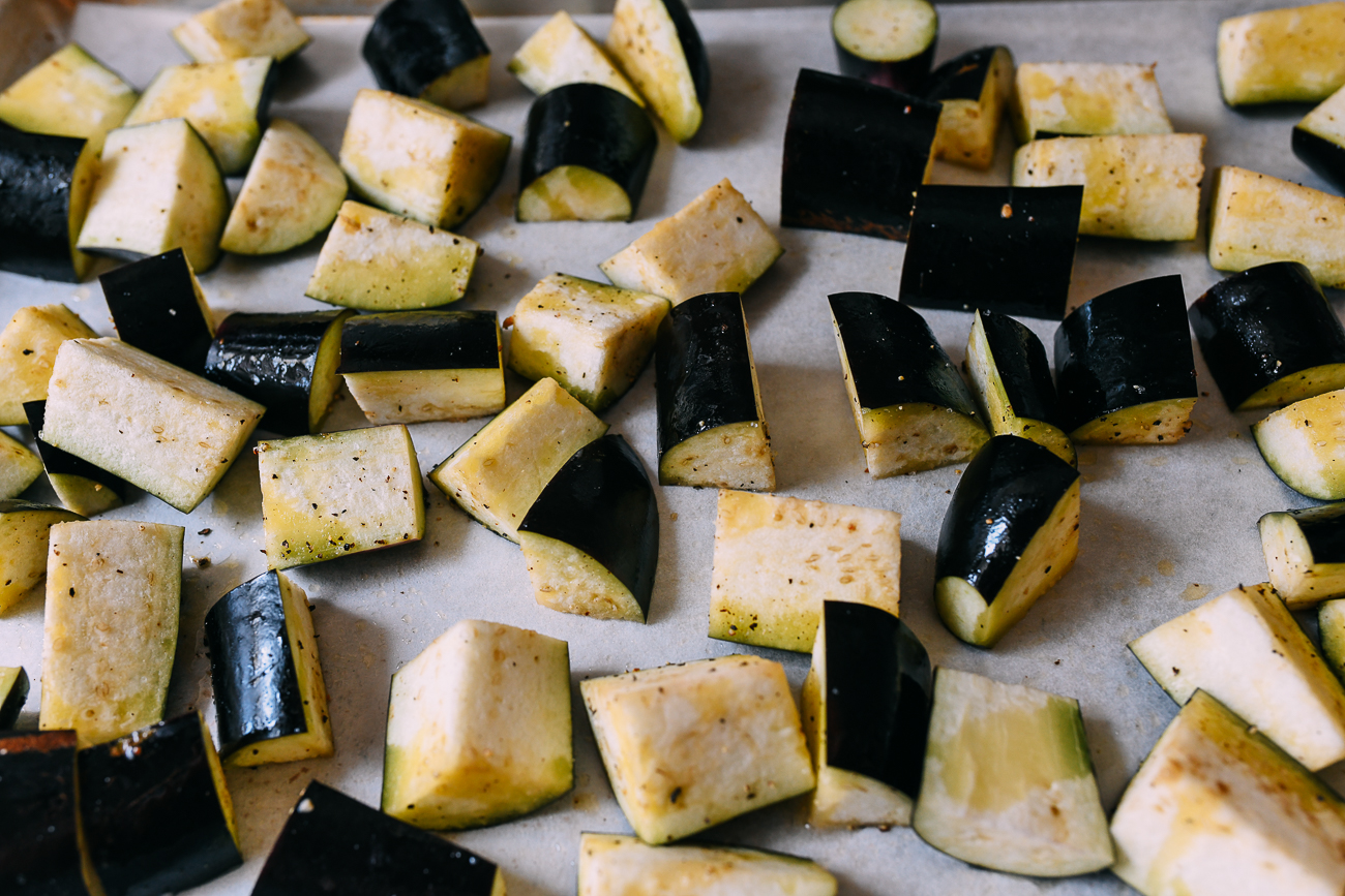 Chunks of eggplant on baking sheet with olive oil, salt and pepper