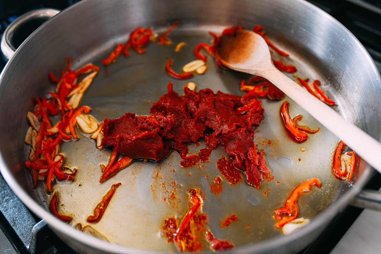 Adding tomato paste to garlic and chilies