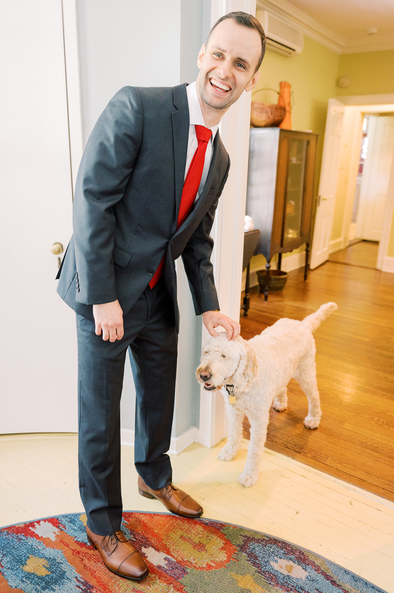 Justin in dark grey suit with red tie petting Barley