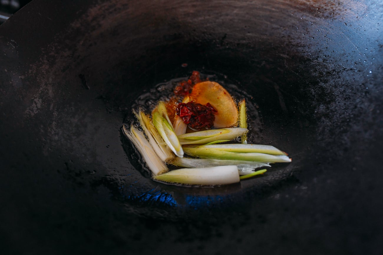 Scallions, ginger, and spicy bean sauce in wok