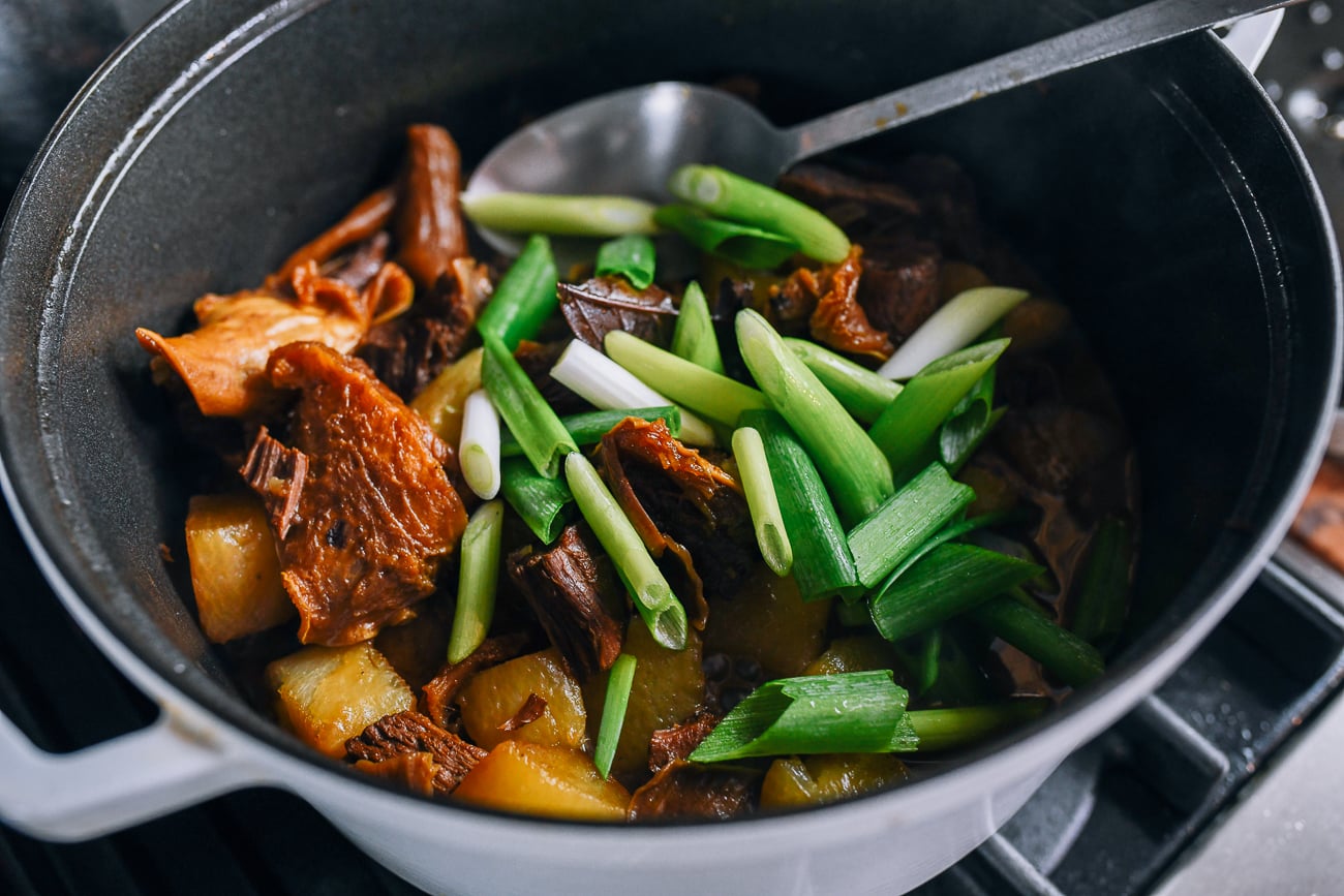 Adding scallions to pot of stew