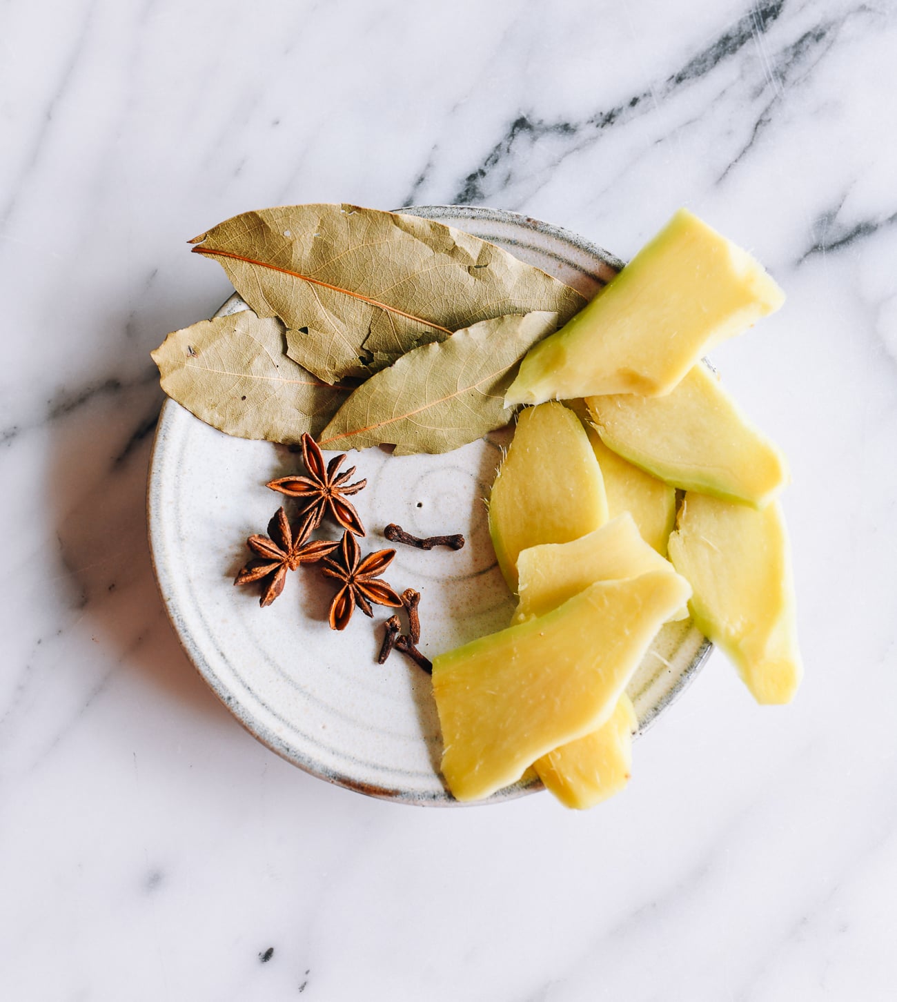 Plate of ginger, bay leaves, cloves and star anise