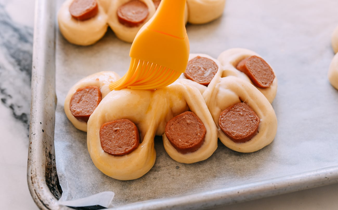 Brushing hot dog buns with egg wash