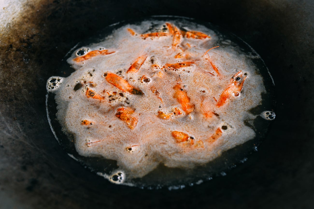 Water added to shrimp shells to make stock in a wok